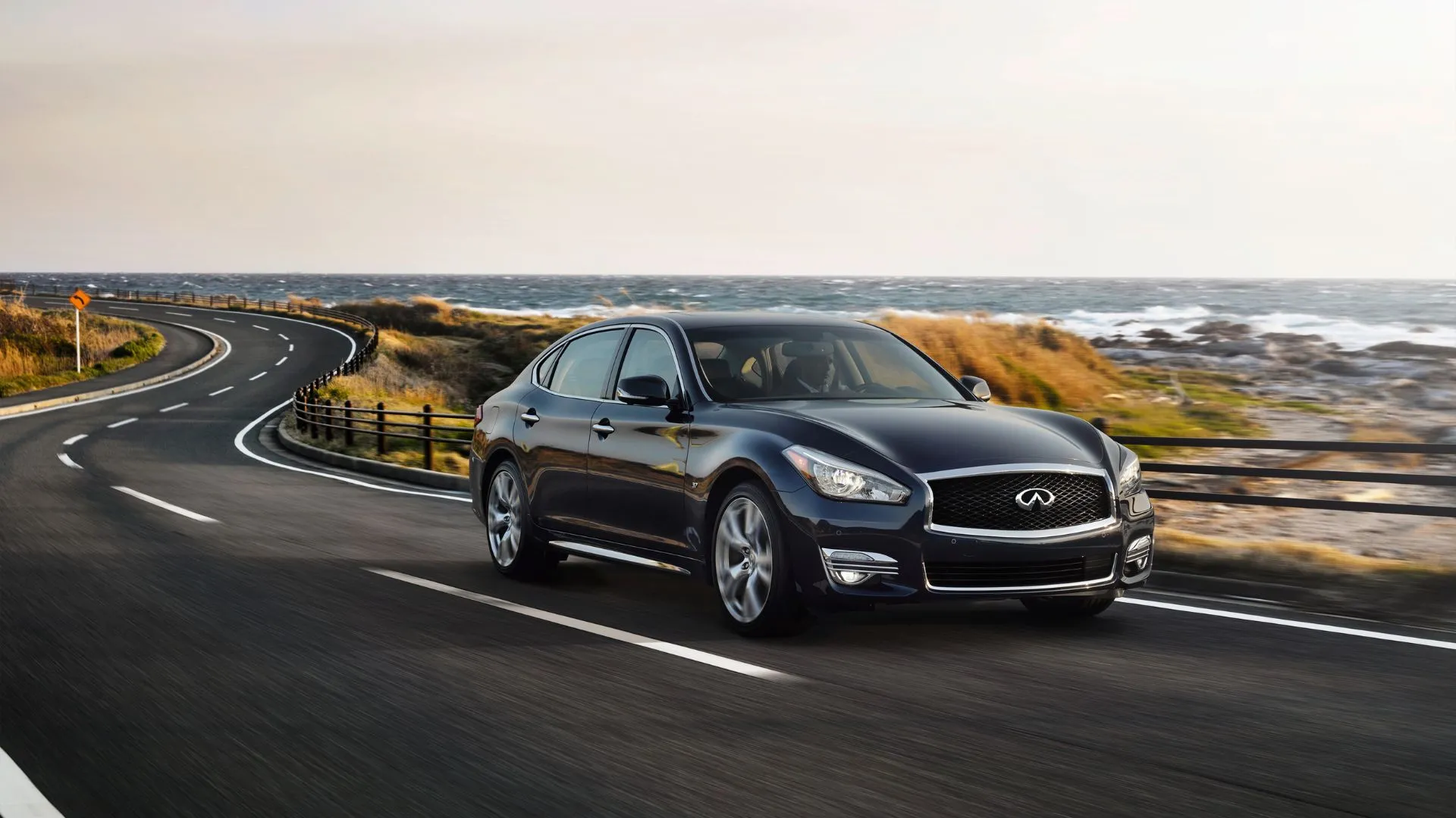 Infiniti Q70L 3.7 Luxe Sedan 2019 đang lướt trên con đường ven biển, nổi bật với thiết kế trục cơ sở dài, động cơ V6 hút khí tự nhiên và không gian nội thất rộng rãi