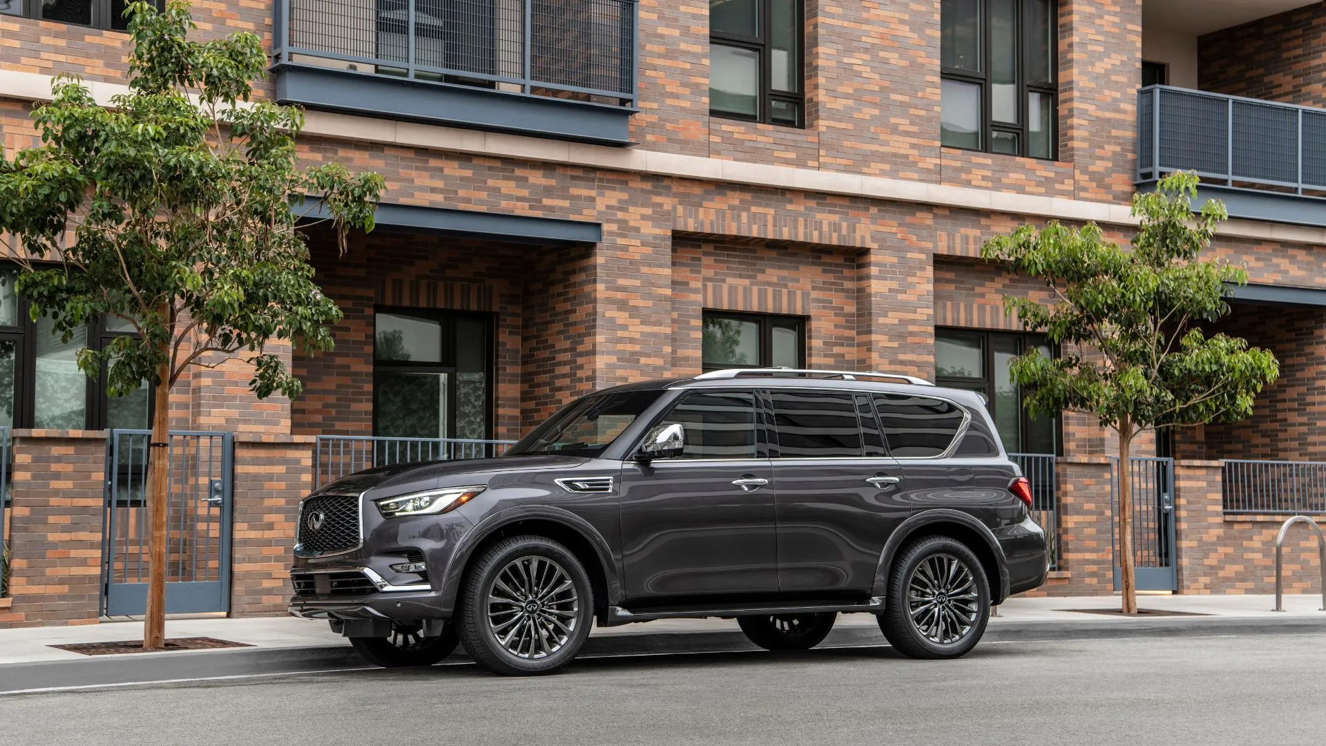 INFINITI QX80 2023 màu xám đỗ ngoài khu dân cư, toát lên phong cách thiết kế táo bạo và hiệu suất mạnh mẽ của SUV cũ.