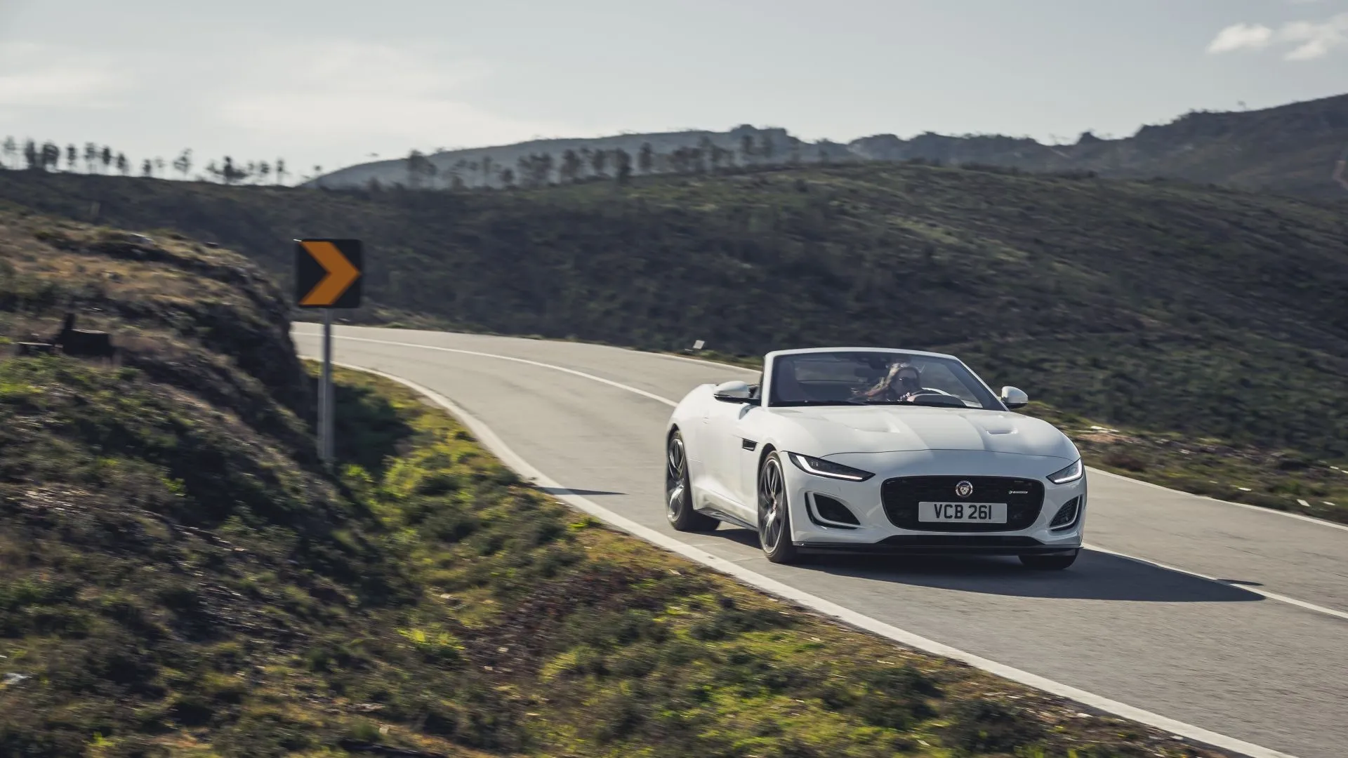 Jaguar F-Type 2022 màu trắng đang chạy trên con đường uốn lượn