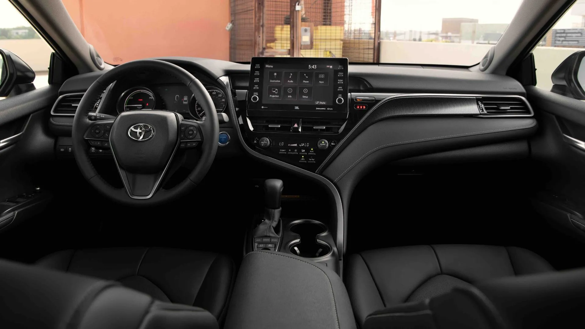 Khoang nội thất màu đen của Toyota Camry Hybrid 2022, với màn hình thông tin giải trí trung tâm và vô lăng, làm nổi bật sự nâng cấp về công nghệ và tiện nghi.
