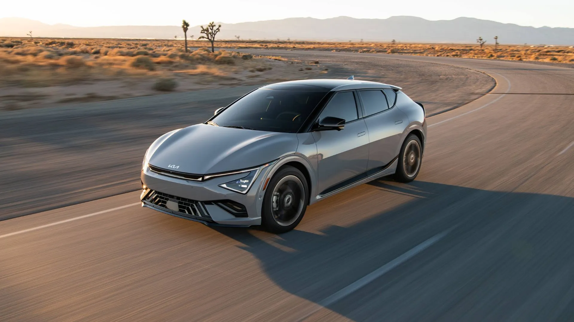 Kia EV6 2025 màu xám di chuyển trên con đường nông thôn, thể hiện thiết kế thể thao và hiện đại