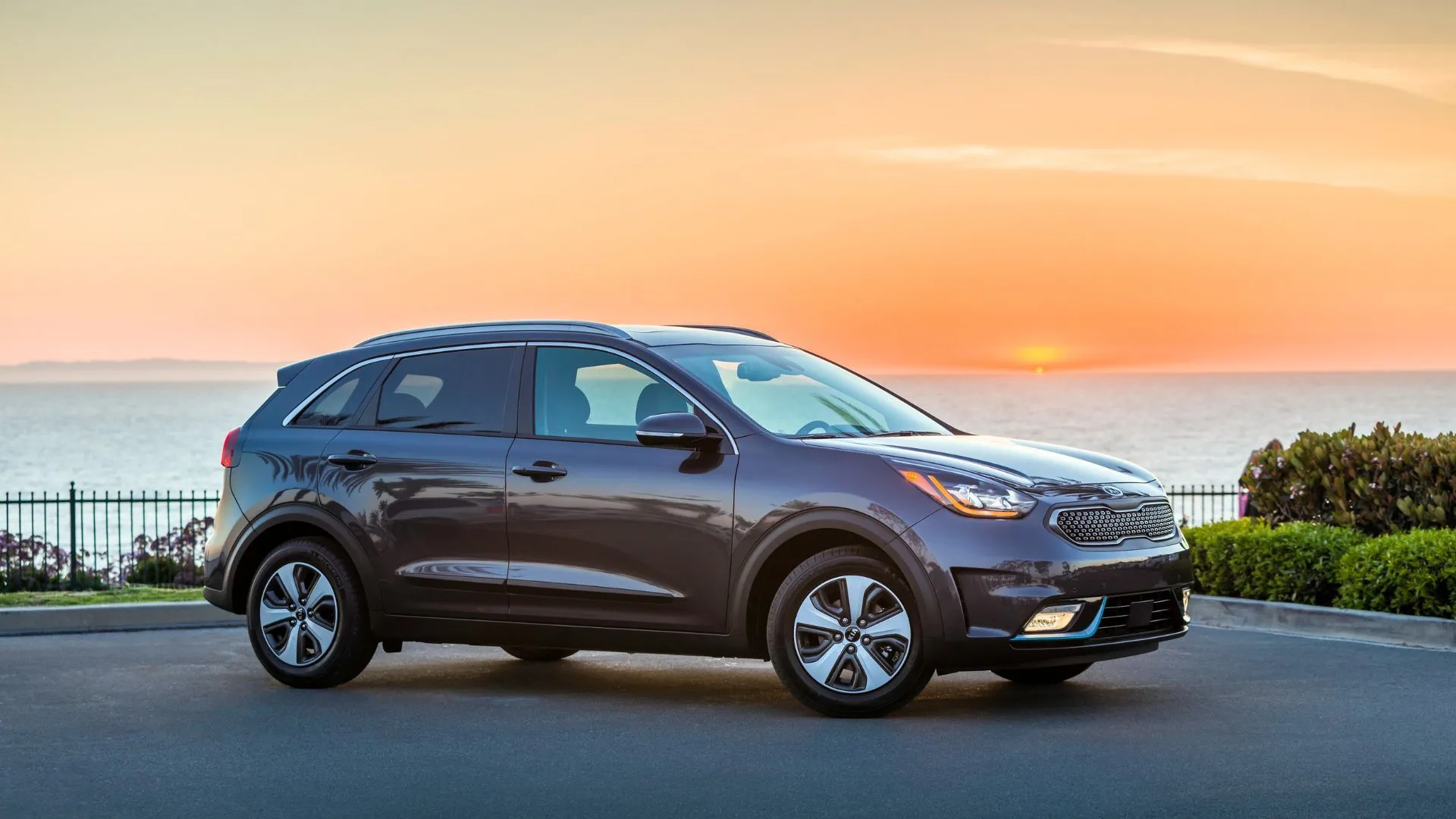 Kia Niro Plug-In Hybrid 2018 màu xám đậu trên đường nhựa khi mặt trời lặn.
