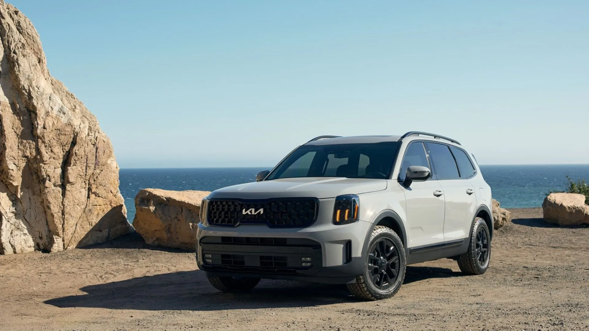 Kia Telluride 2025 màu xám bạc đỗ bên bờ biển với vách đá hùng vĩ