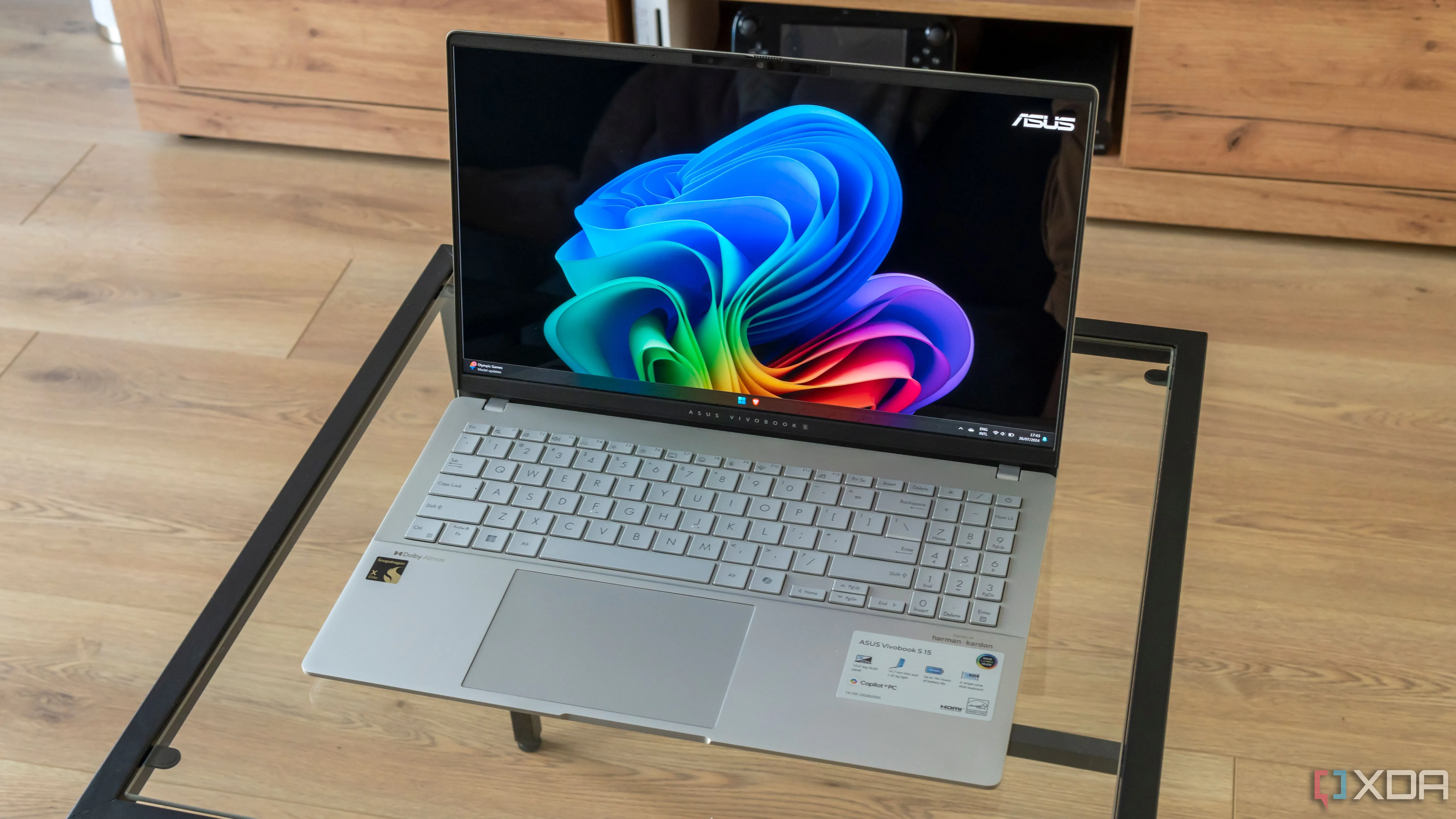 Laptop Asus Vivobook S 15 hiển thị màn hình nền Windows 11 trên bàn kính