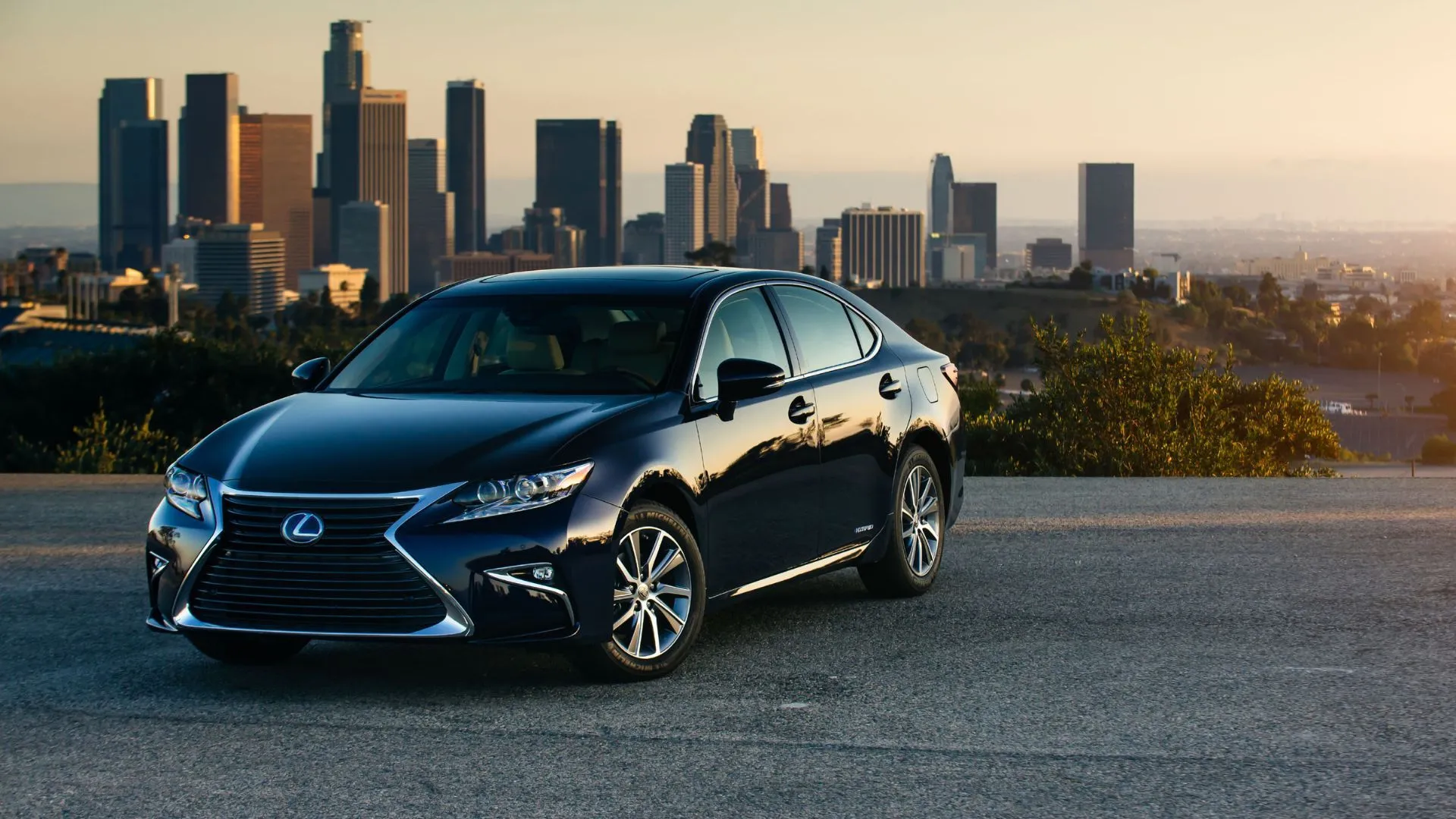 Lexus ES 300h Sedan 2018 màu đen với bối cảnh các tòa nhà chọc trời, minh họa sự kết hợp giữa hiệu quả tiết kiệm nhiên liệu hybrid và sự thoải mái đặc trưng của Lexus ES