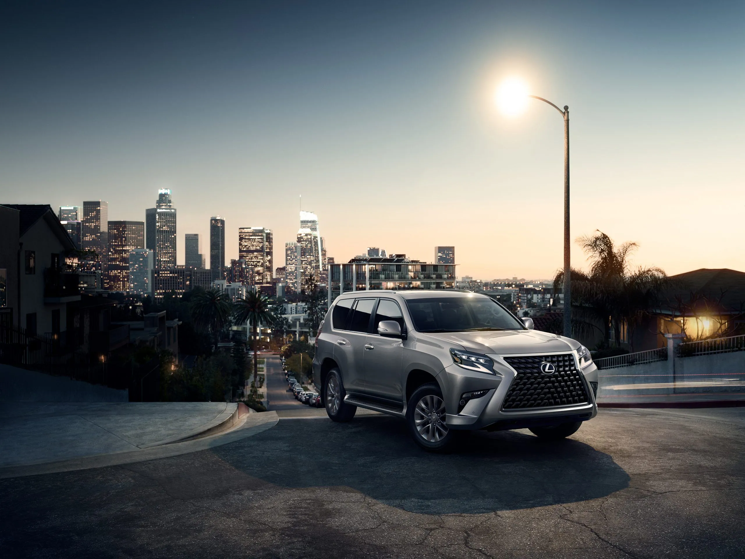 Lexus GX 460 2022 màu bạc đỗ trên đường dưới đèn đường với khung cảnh thành phố phía sau