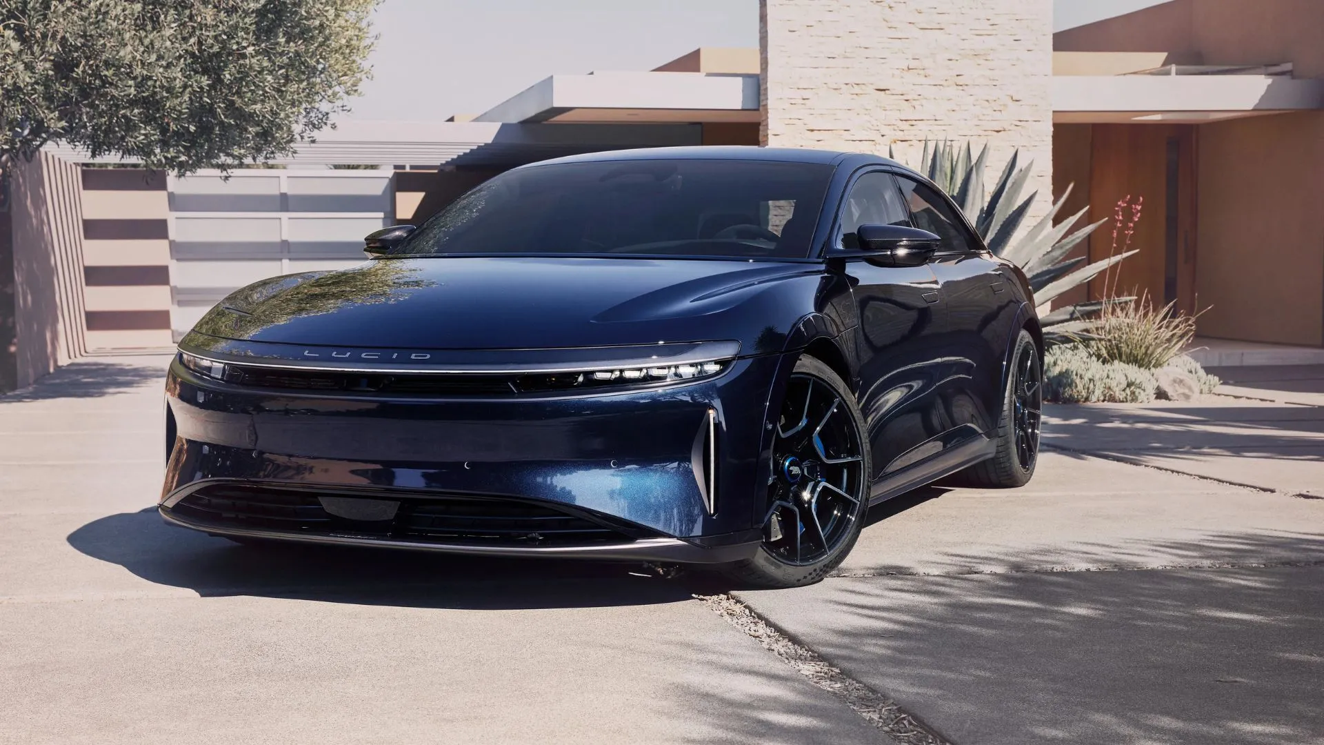 Mặt trước của chiếc Lucid Air Sapphire màu xanh lam đậu trên đường lái xe bên ngoài một ngôi nhà.