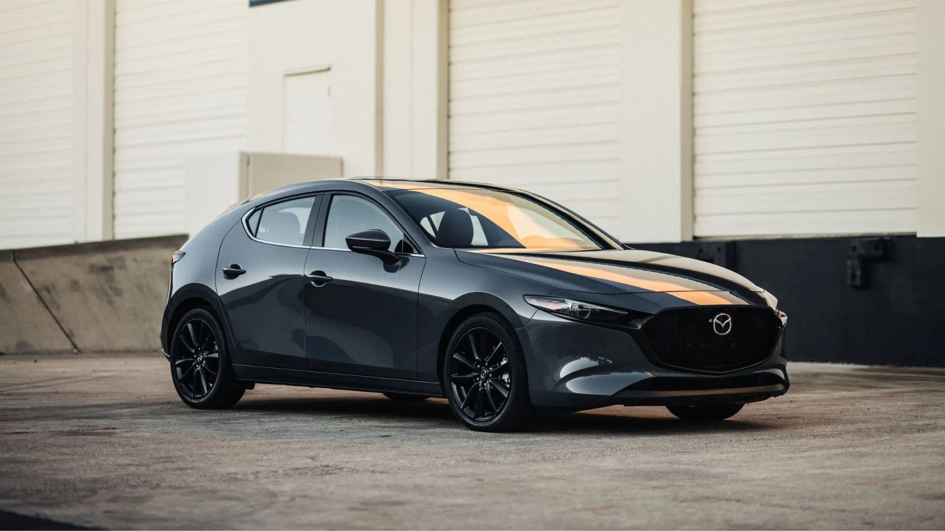 Mazda3 2.5 Turbo Premium Plus 2025 màu đen đỗ ngoài trời, phía sau là nhà kho.