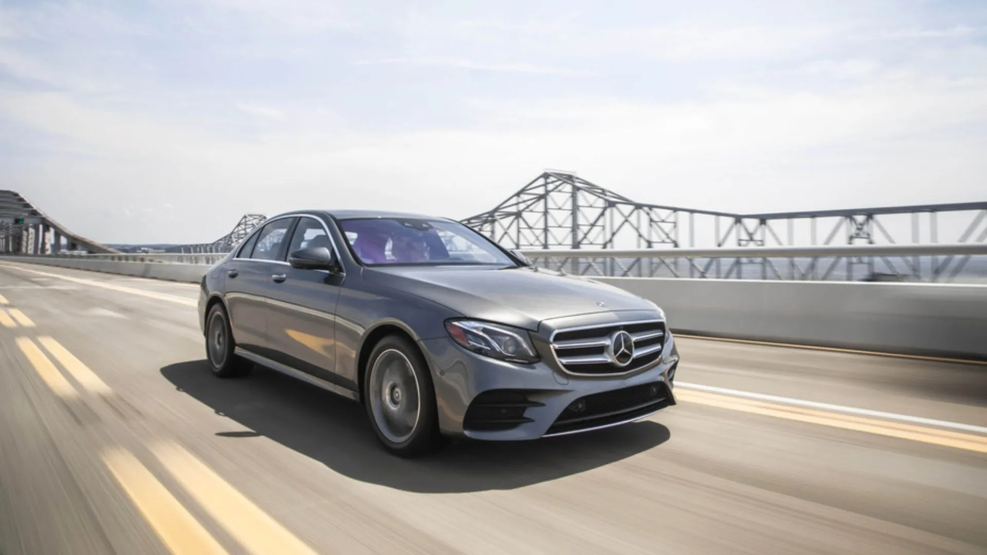 Mercedes-Benz E 300 4MATIC Sedan 2019 màu xám đang lướt trên cầu, toát lên vẻ sang trọng, tinh tế và khả năng vận hành êm ái của dòng xe sedan hạng sang Mercedes