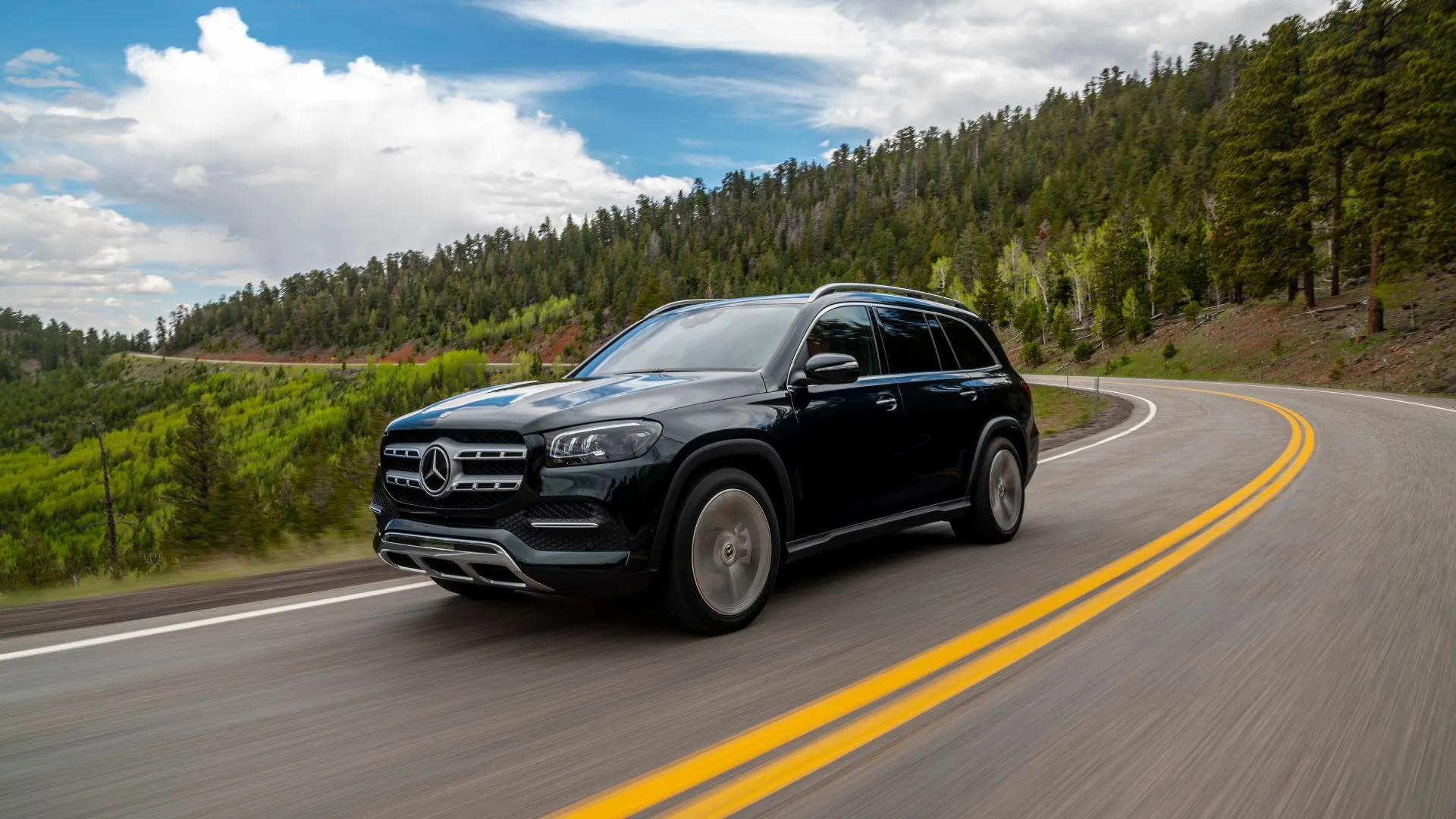 Mercedes-Benz GLS 2021 màu đen chạy trên đường nông thôn uốn lượn, hình ảnh đại diện cho sự sang trọng và êm ái của SUV hàng đầu đã qua sử dụng.