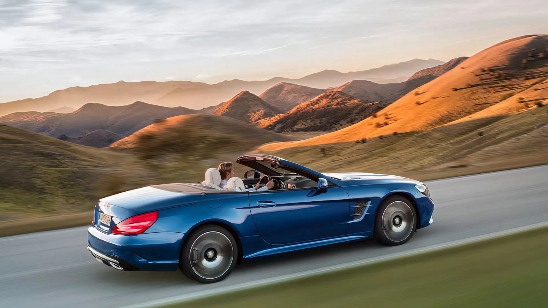 Mercedes-Benz SL-Class màu xanh dương đang chạy trên đường nông thôn với mui hạ