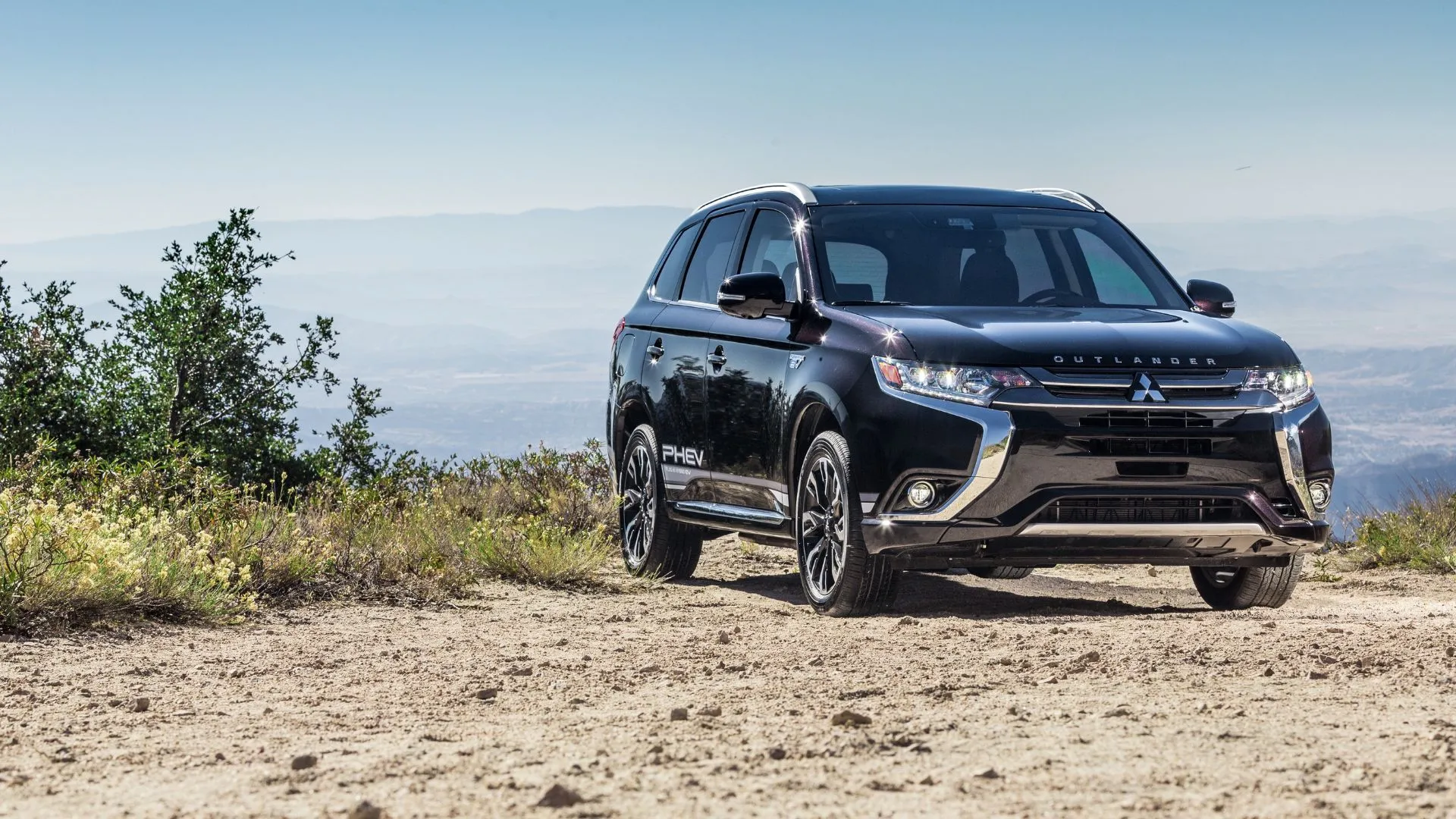 Mitsubishi Outlander PHEV 2018 màu đen đỗ trên nền sỏi, góc nhìn phía trước.