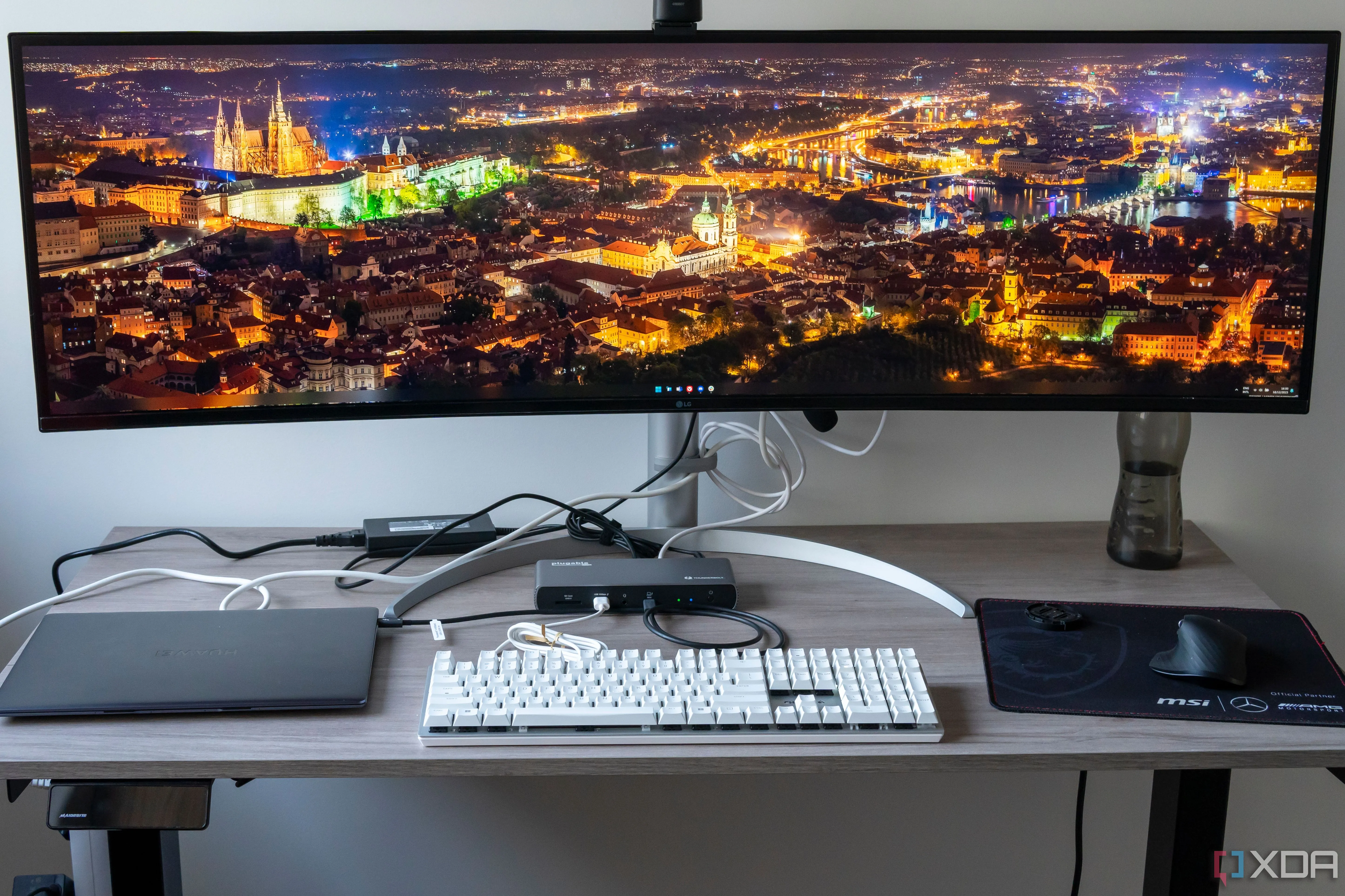 Một bàn làm việc với màn hình, bàn phím, chuột và laptop được kết nối qua docking station Plugable TBT4-UDX1
