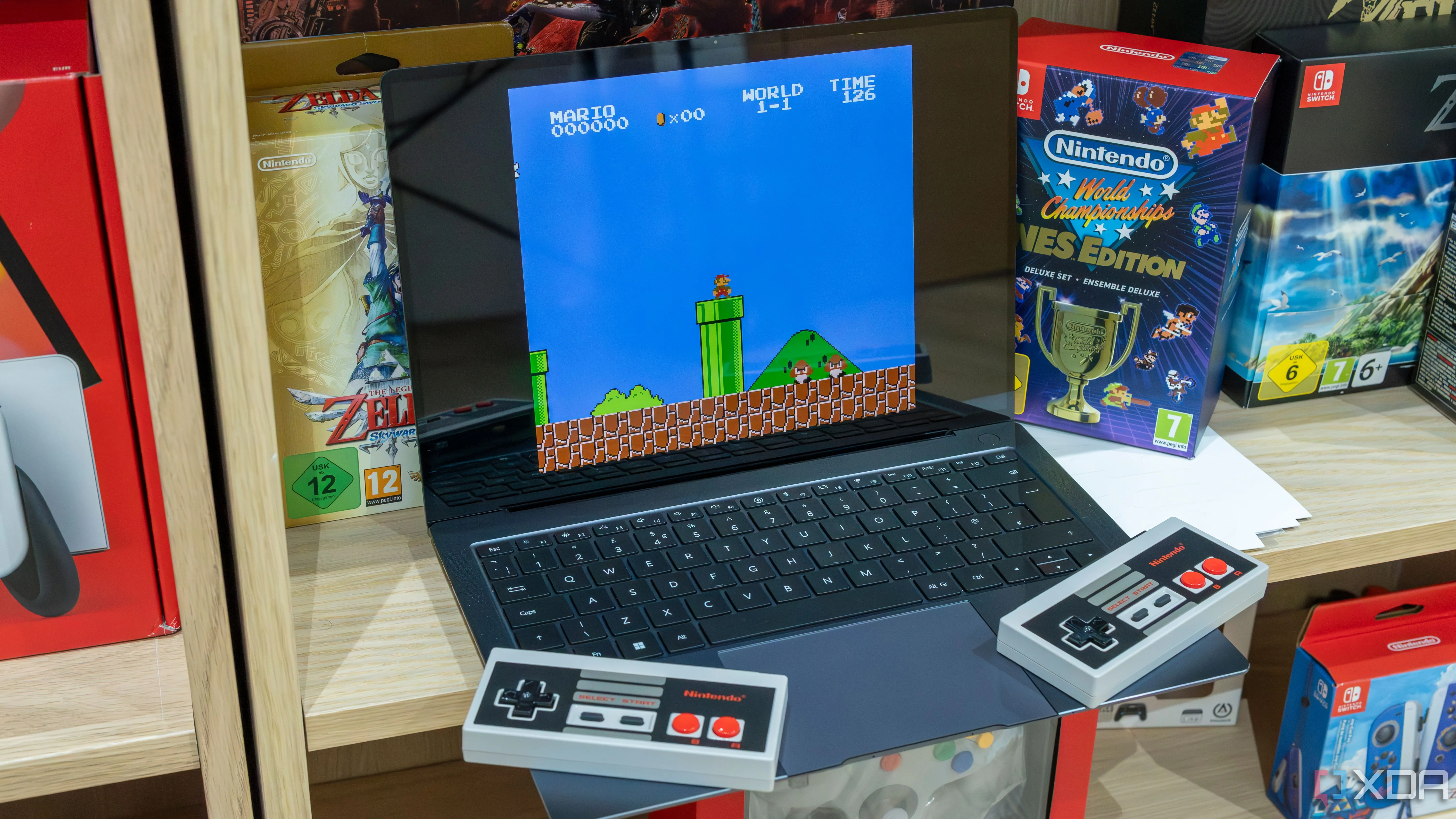 Một chiếc laptop chạy Windows 11 đang giả lập game Super Mario Bros cổ điển, bên cạnh là hai tay cầm NES không dây.