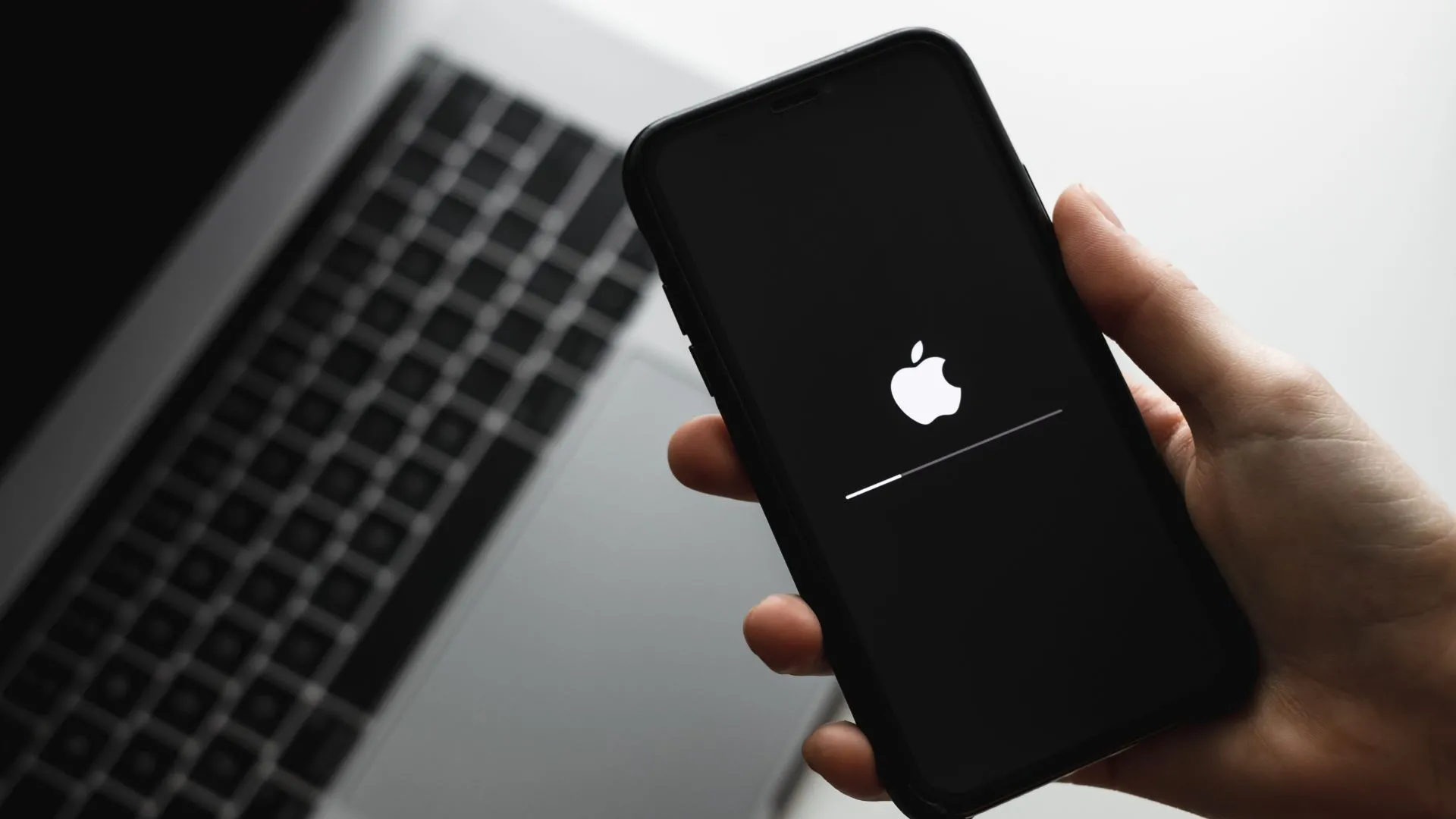 Một người đang cầm iPhone trong tay khi thiết bị thực hiện cập nhật phần mềm, minh họa sự tiện lợi của việc cập nhật ứng dụng điều hướng trên smartphone.