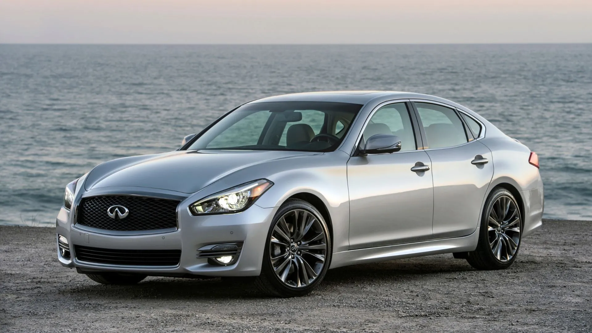Ngoại thất phía trước bên phải của Infiniti Q70 2017 màu bạc đỗ trên bãi biển