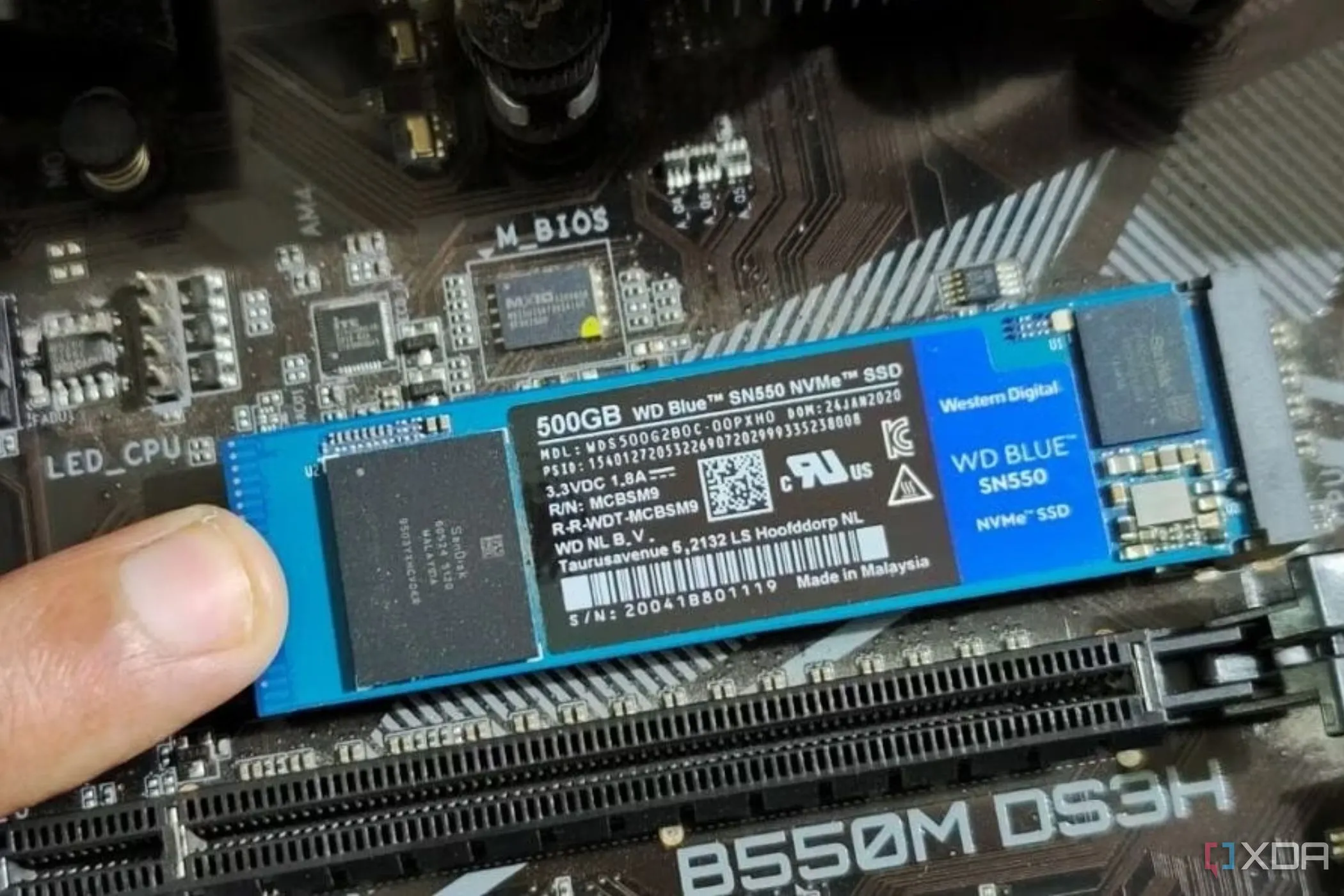 Người dùng đang giữ mô-đun SSD M.2 trên bo mạch chủ, minh họa việc lắp đặt SSD M.2 cần chú ý đến ốc standoff.