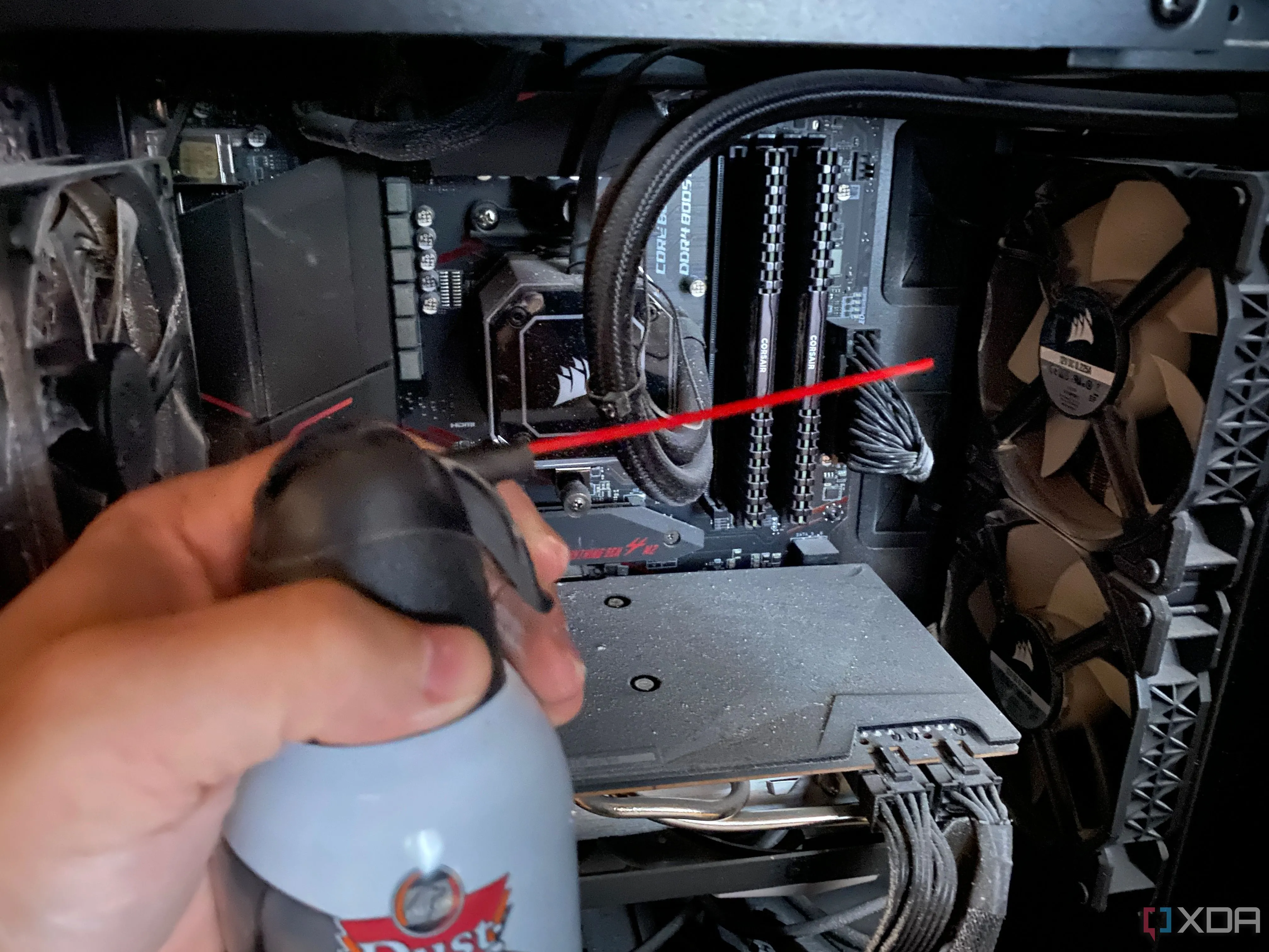Người dùng đang sử dụng bình xịt khí nén để làm sạch bụi bên trong vỏ case máy tính gaming, giúp cải thiện luồng khí và tản nhiệt.