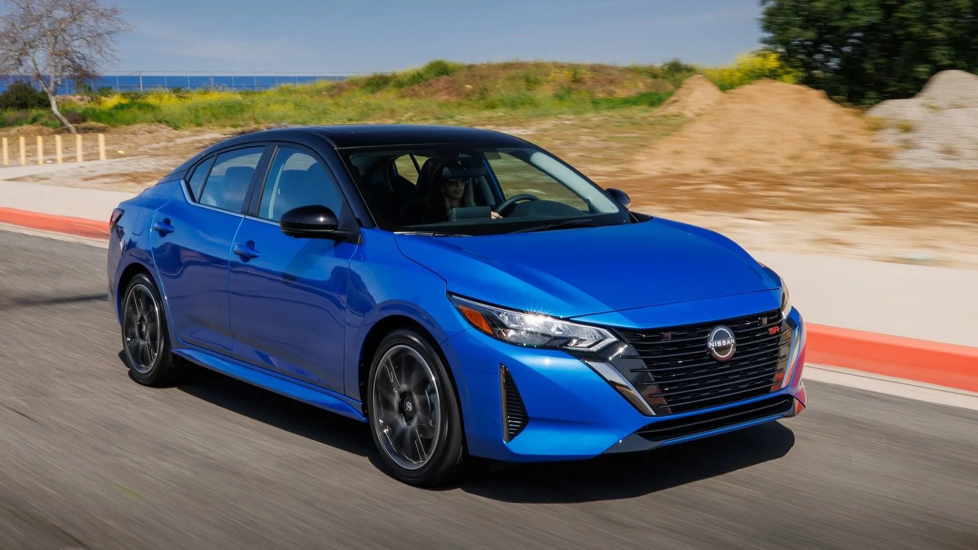 Nissan Sentra 2024 màu xám bạc đang di chuyển trên đường phố với năng động