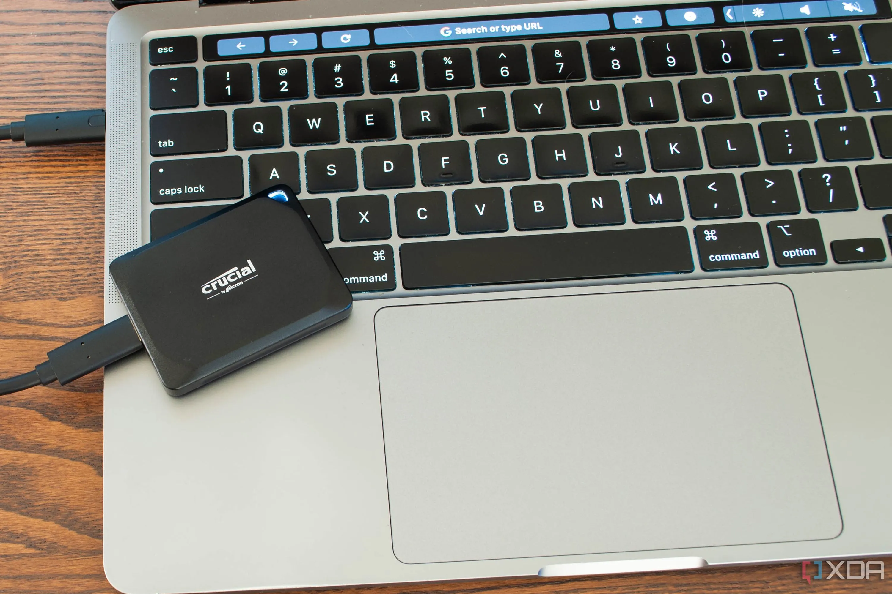 Ổ cứng SSD di động Crucial X10 Pro nhỏ gọn đặt cạnh laptop, minh họa sự tiện lợi khi làm việc đa thiết bị