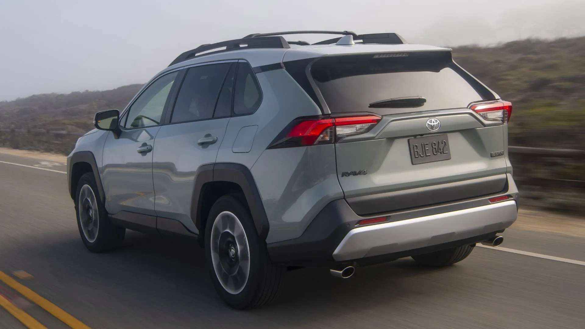 Phần đuôi xe Toyota RAV4 Adventure 2020 màu xám di chuyển trên con đường nông thôn, nhấn mạnh khả năng vận hành linh hoạt và không gian rộng rãi.