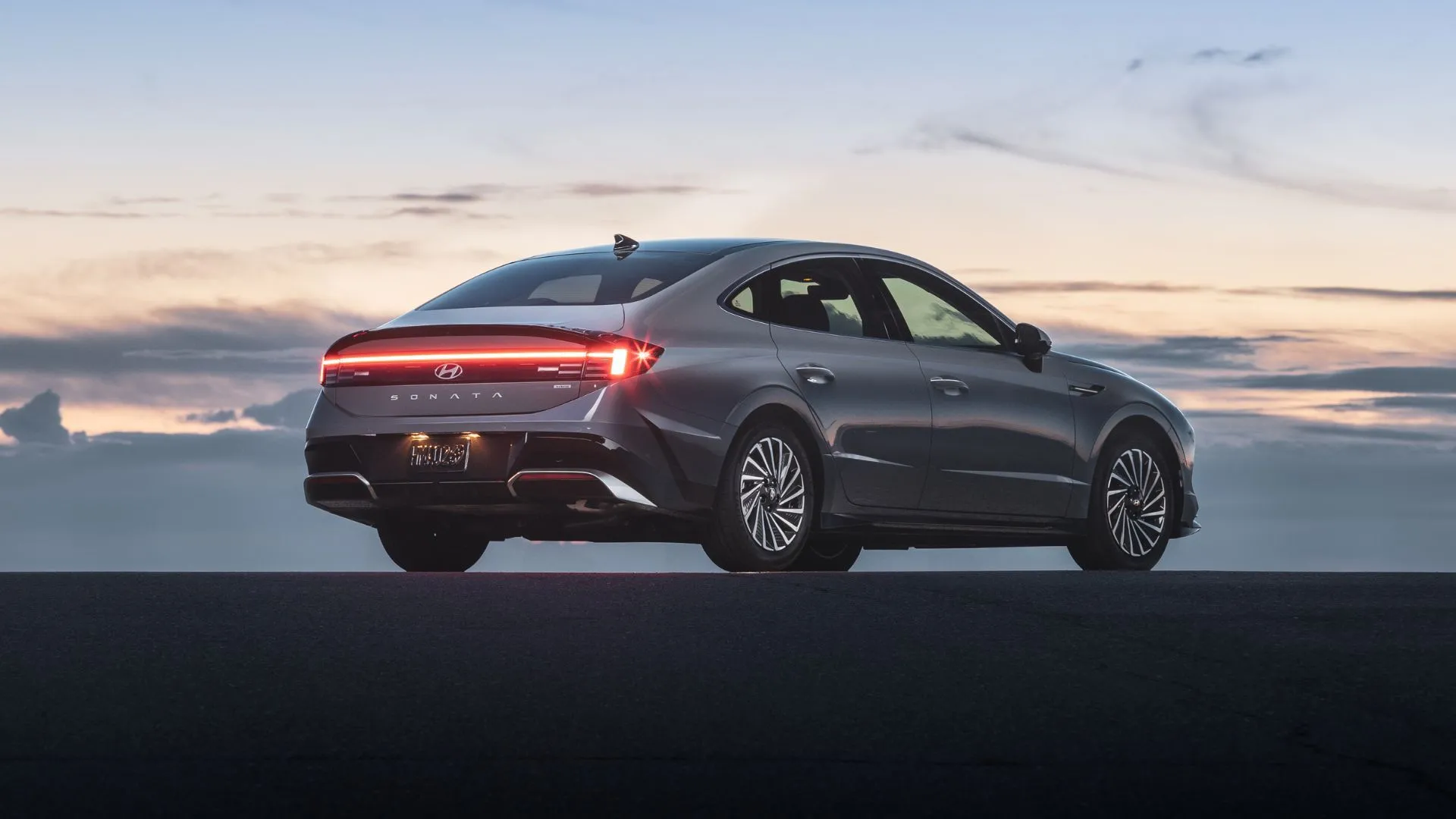 Phần thân sau ấn tượng của Hyundai Sonata Hybrid Limited 2025 màu xám bạc, nổi bật dưới ánh hoàng hôn với thiết kế đèn LED độc đáo