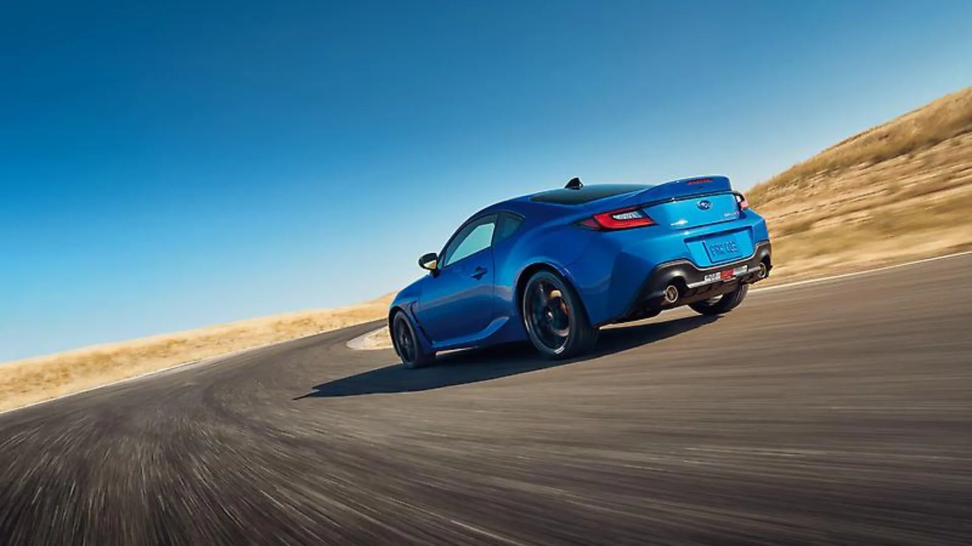 Subaru BRZ tS 2024 màu xanh dương đang vào cua trên đường nông thôn, góc 3/4 phía sau