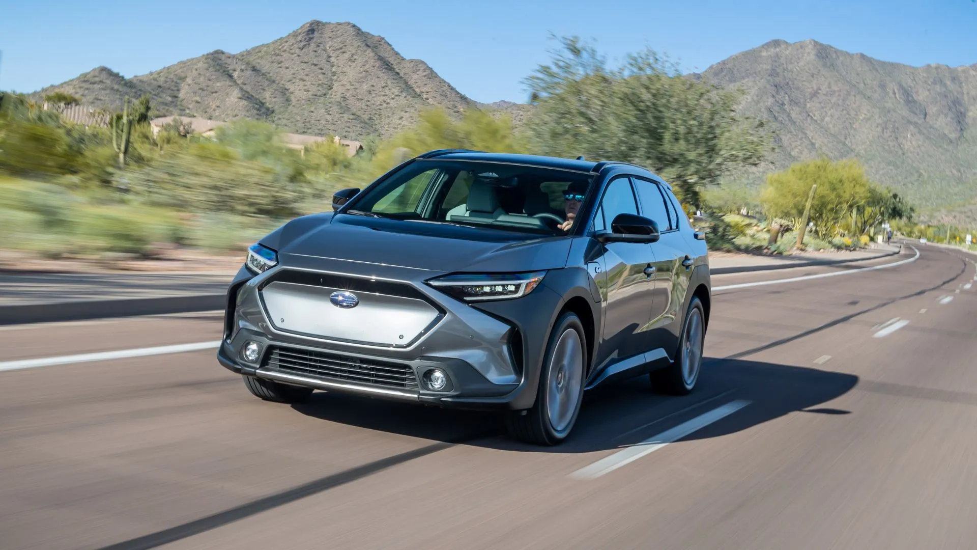 Subaru Solterra 2024 màu xám trên đường quê với núi