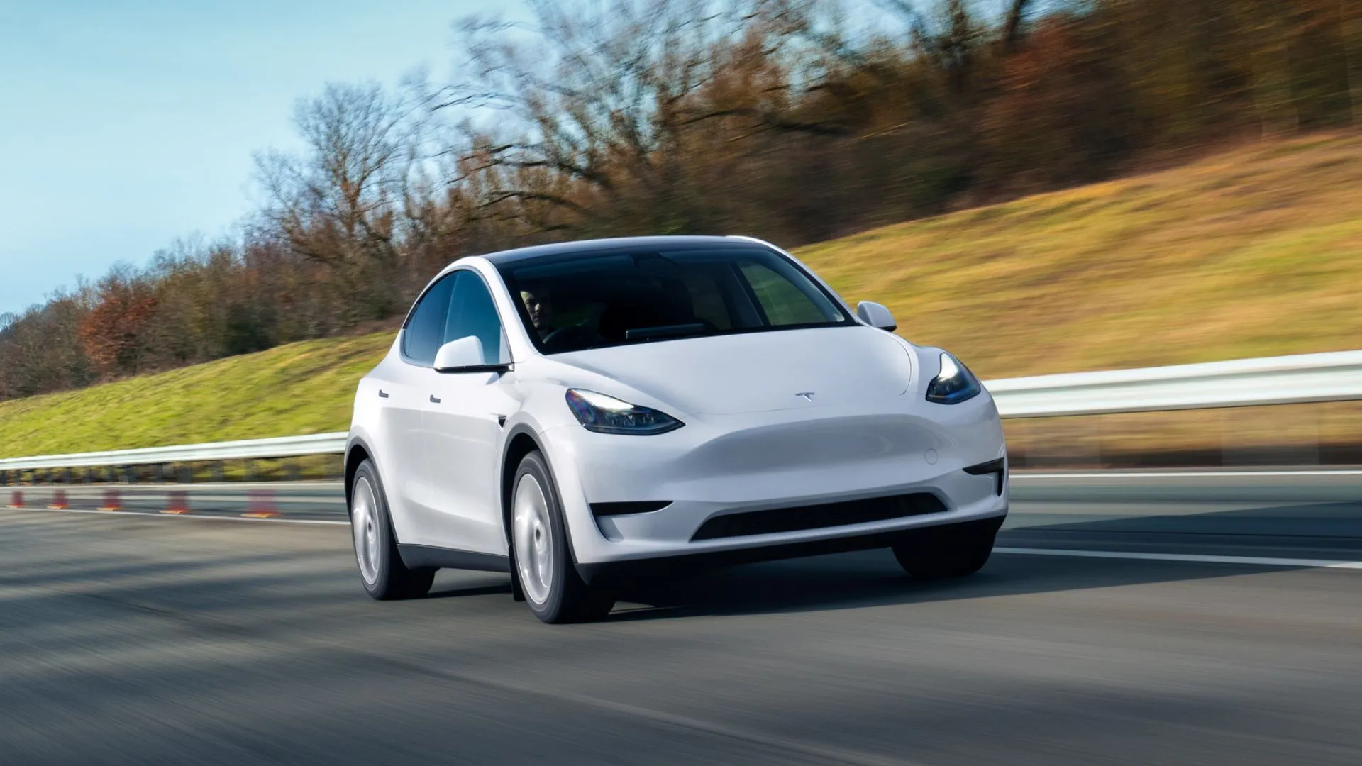 Tesla Model Y màu trắng di chuyển trên đường cao tốc, đại diện cho dòng SUV điện gia đình với khả năng tăng tốc ấn tượng.