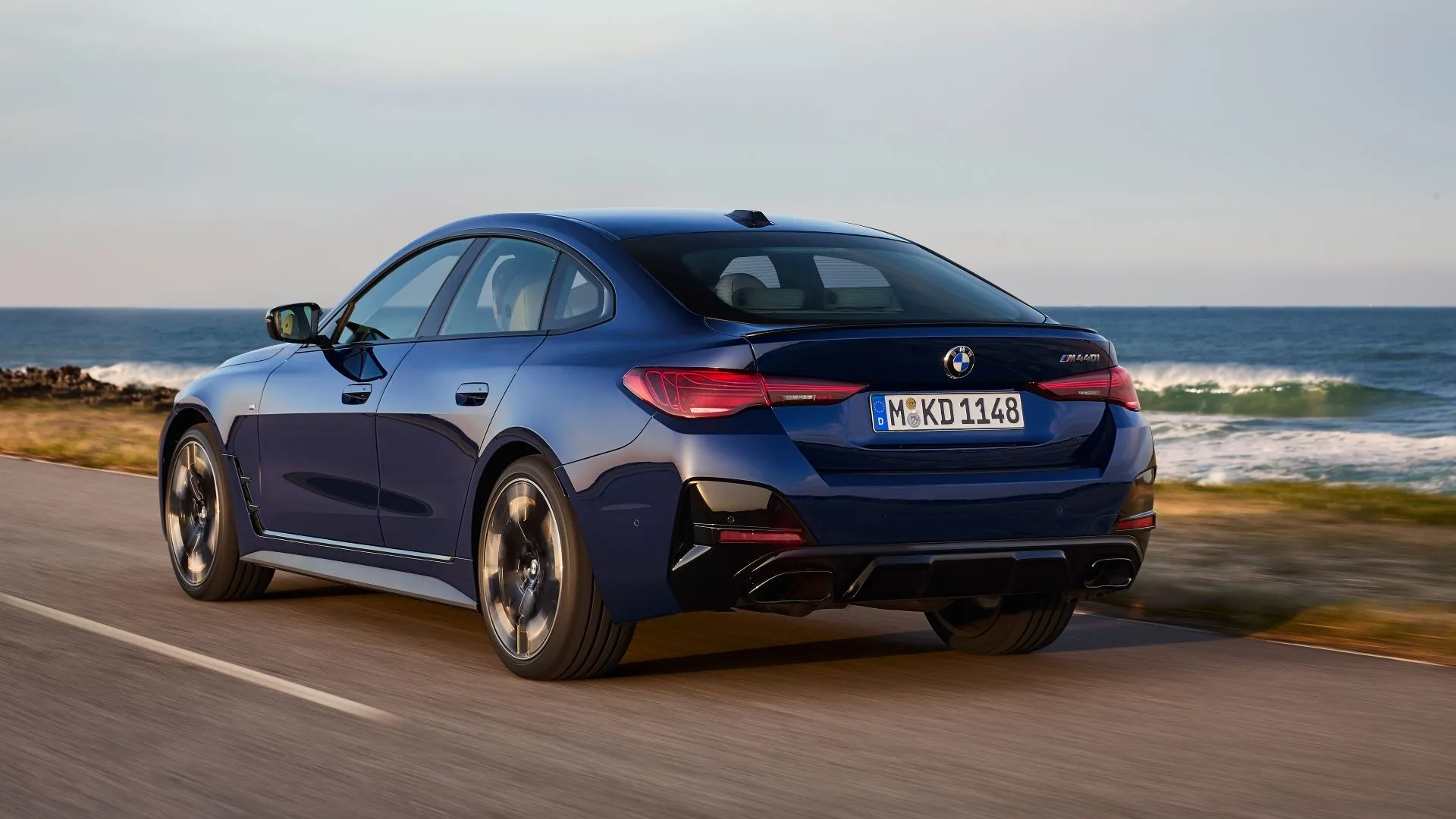 Thân xe BMW i4 2025 màu xanh bạc di chuyển trên đường cho thấy thiết kế thể thao