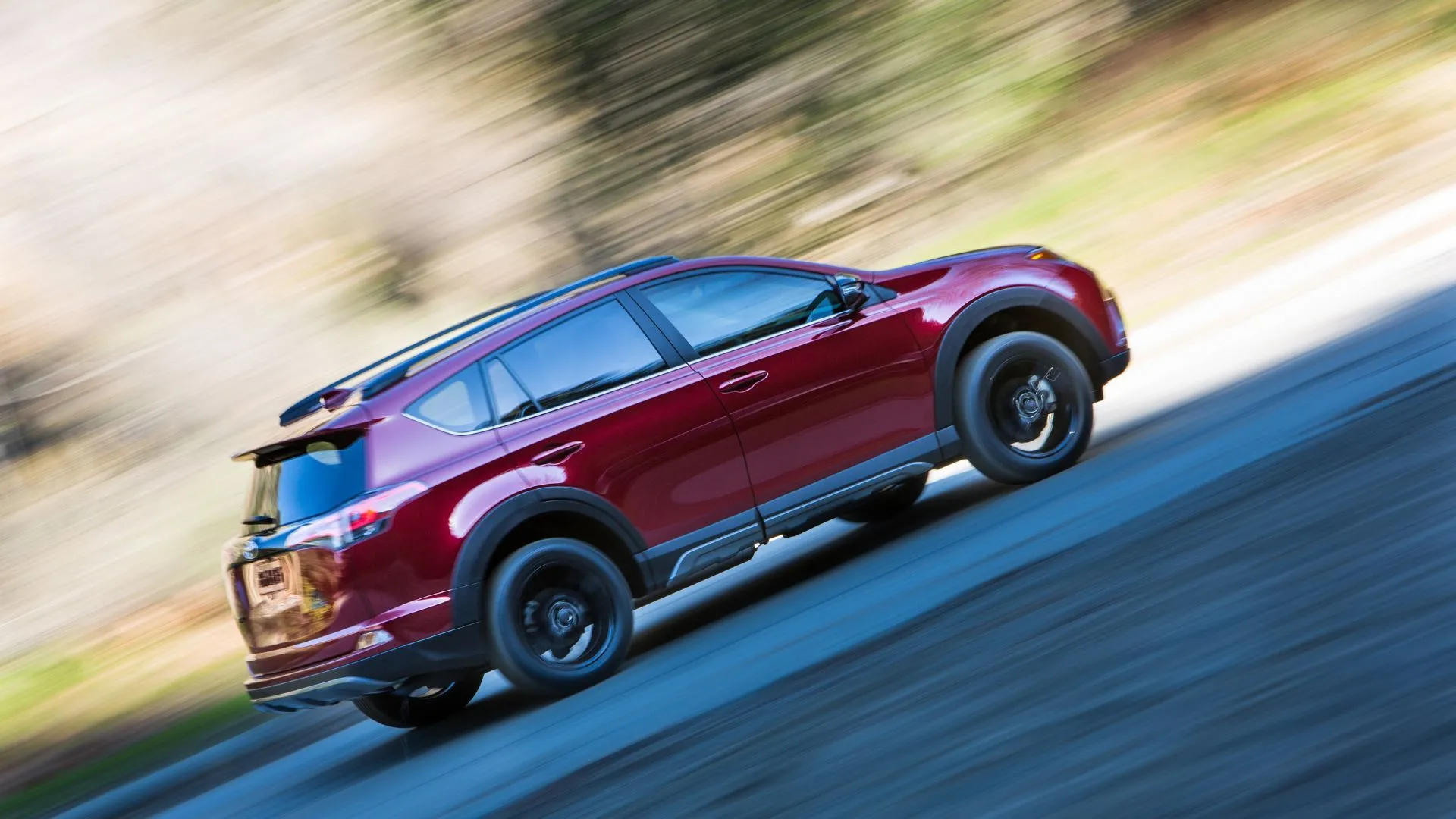 Thân xe Toyota RAV4 Adventure 2018 màu xanh lá đang di chuyển trên đường quê, thể hiện thiết kế mạnh mẽ và linh hoạt.