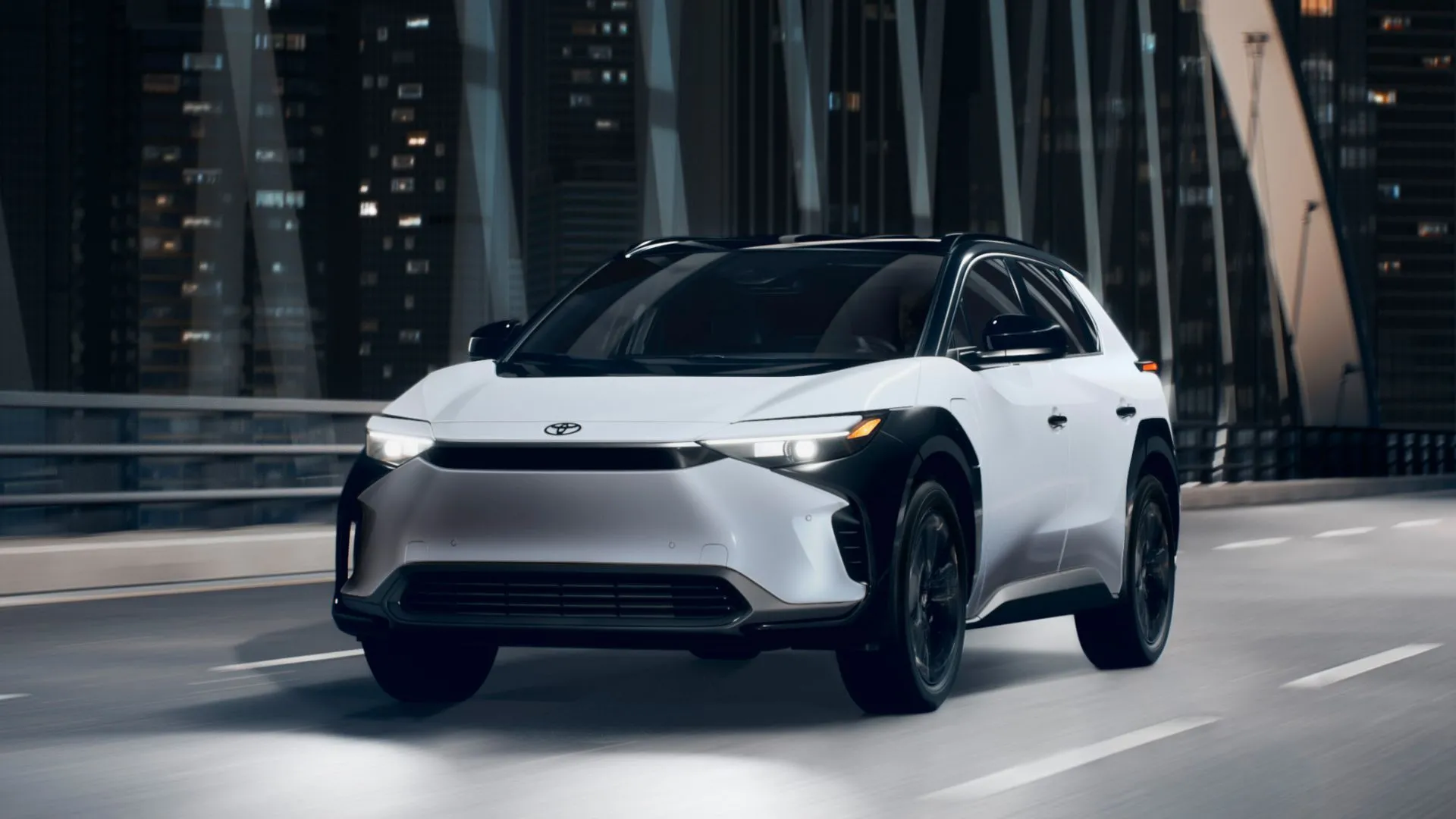 Toyota bZ4X Limited AWD 2025 màu trắng di chuyển trên cầu thành phố vào ban đêm, nhắc nhở người mua xe điện kiểm tra tình trạng đăng ký tín dụng thuế.
