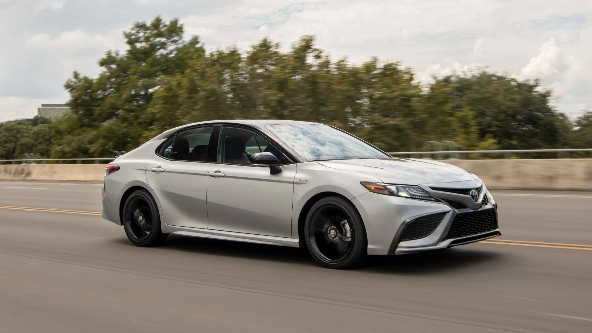 Toyota Camry Hybrid 2023 cũ màu bạc đang lướt trên đường cao tốc, thể hiện sự bền bỉ và hiệu suất.