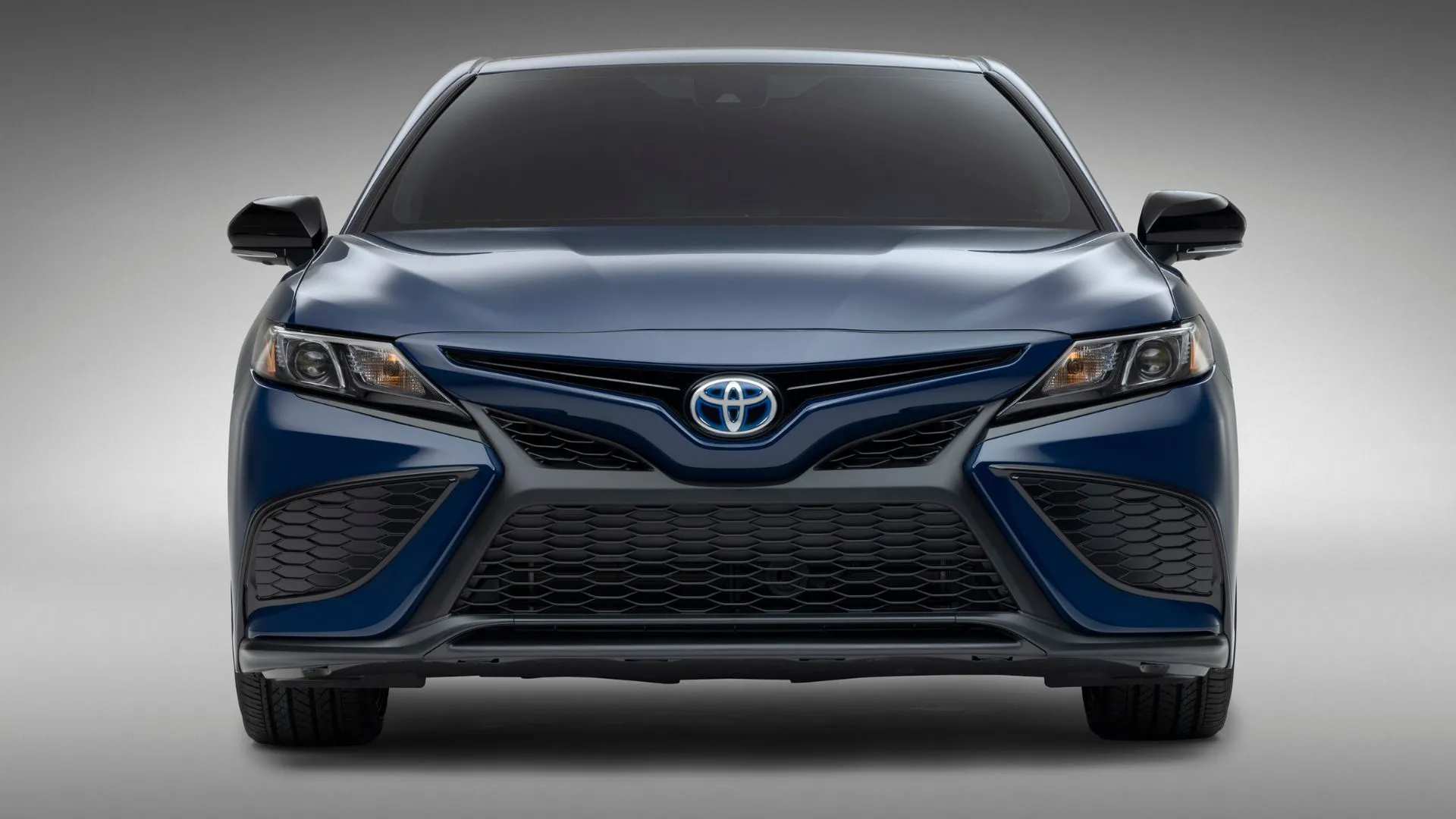 Toyota Camry Hybrid 2023 màu xanh nổi bật trong không gian studio, cho thấy thiết kế sang trọng.