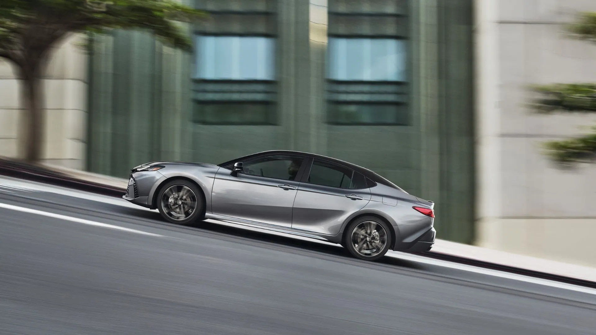 Toyota Camry XSE 2025 màu xám đang lái lên dốc trong thành phố.