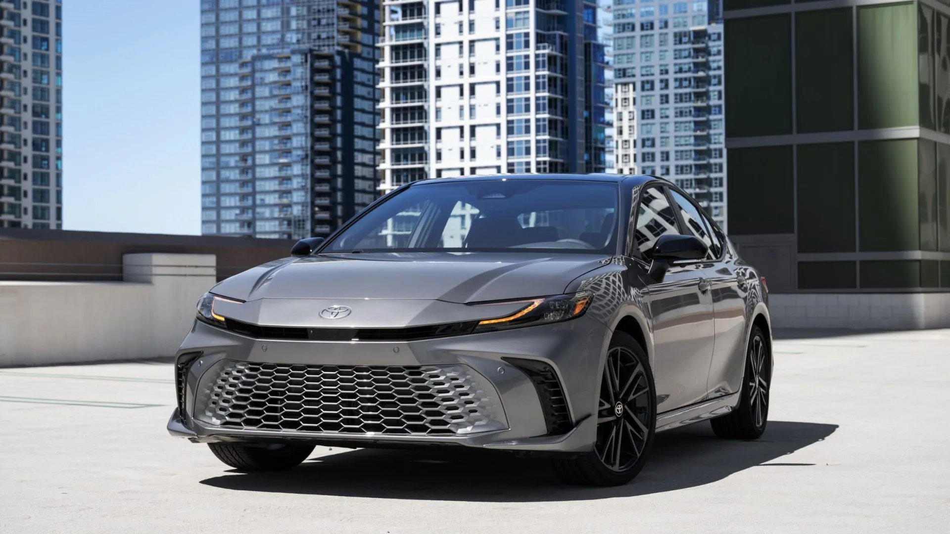 Toyota Camry XSE AWD 2025 màu xám đỗ cạnh tòa nhà cao tầng.