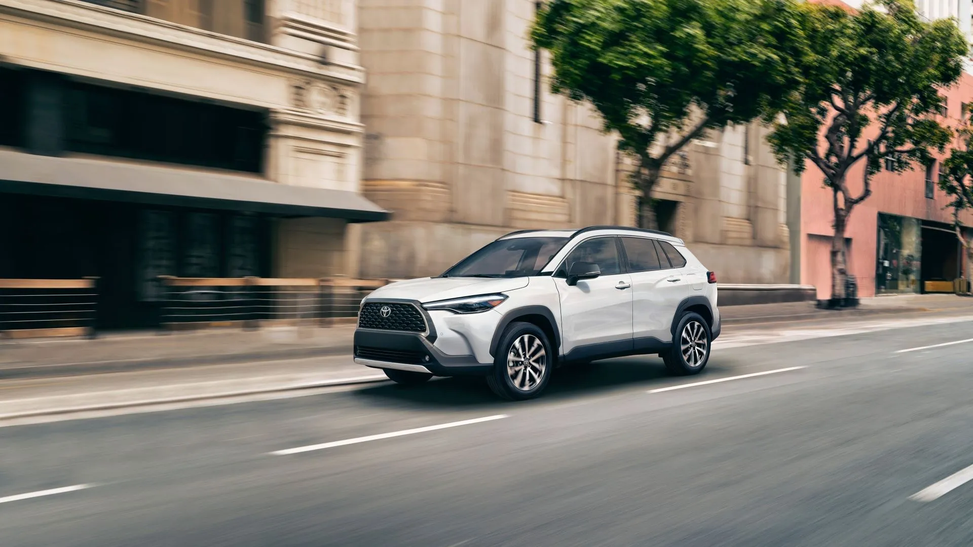Toyota Corolla Cross 2025 màu trắng ngọc trai, ảnh chụp 3/4 phía trước, nổi bật với sự thực dụng và nhiều tính năng an toàn, có tùy chọn AWD.