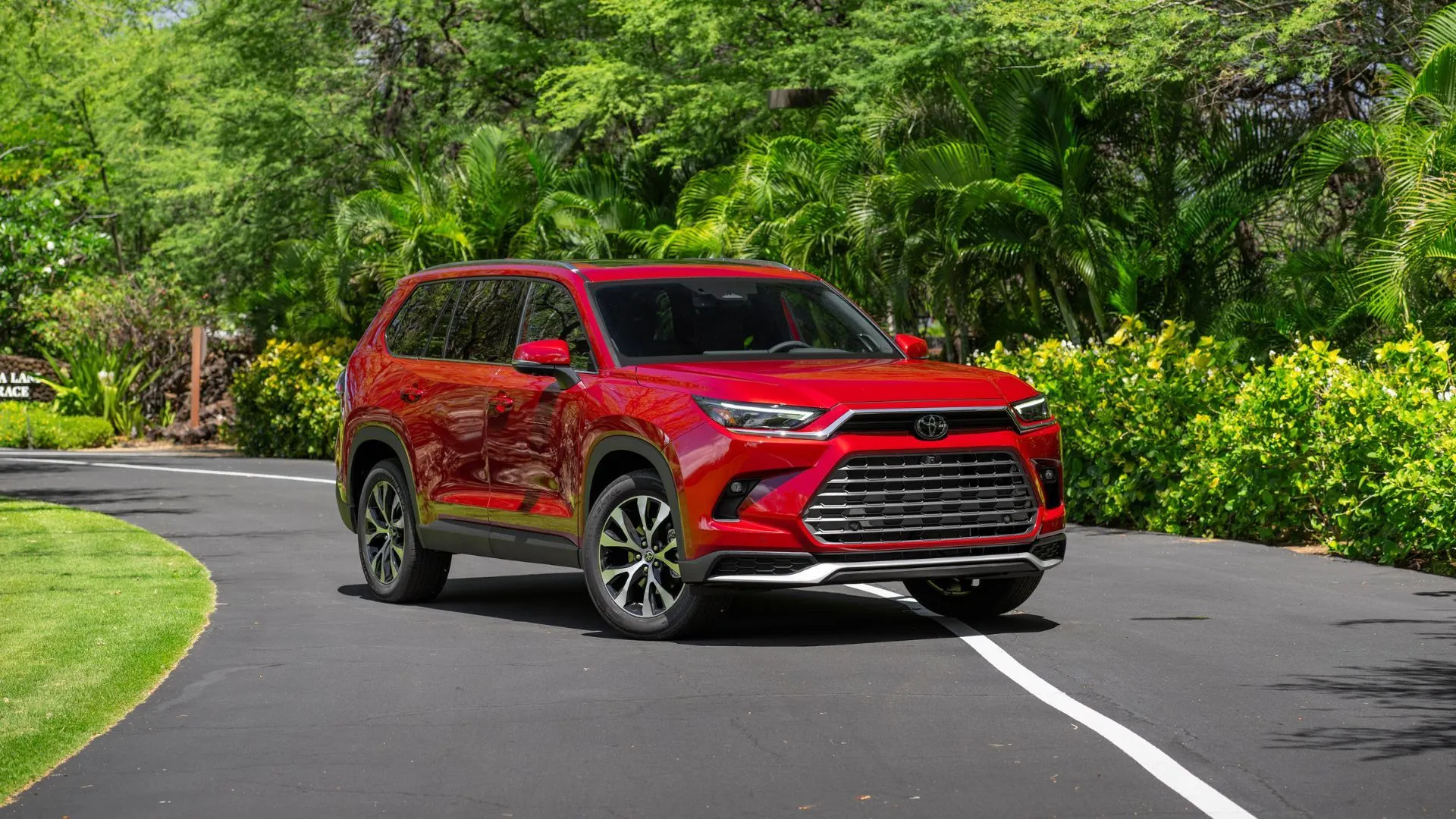 Toyota Grand Highlander Hybrid 2025 màu đỏ Ruby Flare Pearl đỗ ngang đường, nhấn mạnh thiết kế thể thao