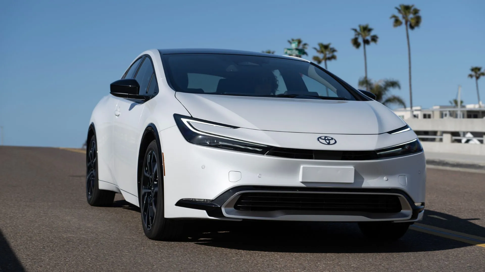 Toyota Prius PHEV XSE 2025 màu trắng di chuyển trên cầu.