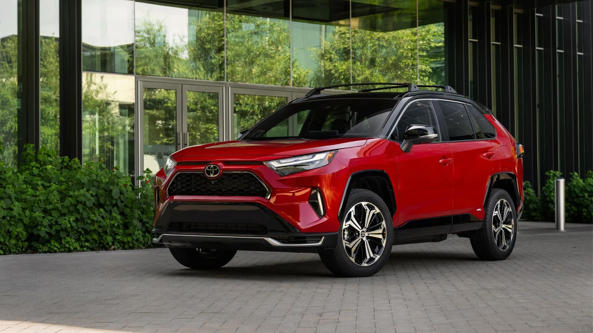Toyota RAV4 Plug-in Hybrid XSE 2025 màu đỏ đỗ phía trước tòa nhà hiện đại, thể hiện phong cách SUV đẳng cấp.