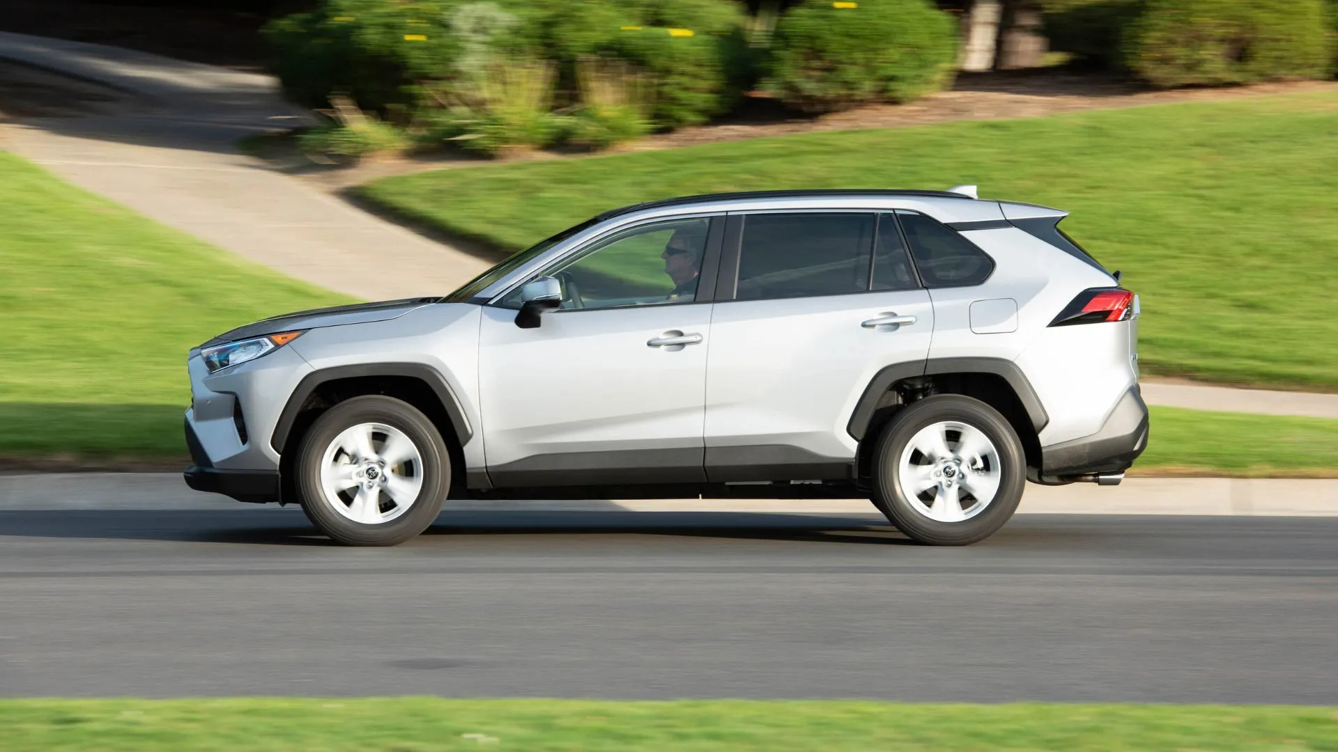 Toyota RAV4 XLE FWD 2019 màu bạc lướt nhẹ qua khu dân cư, thể hiện sự linh hoạt và hiệu quả vận hành của động cơ 2.5L.